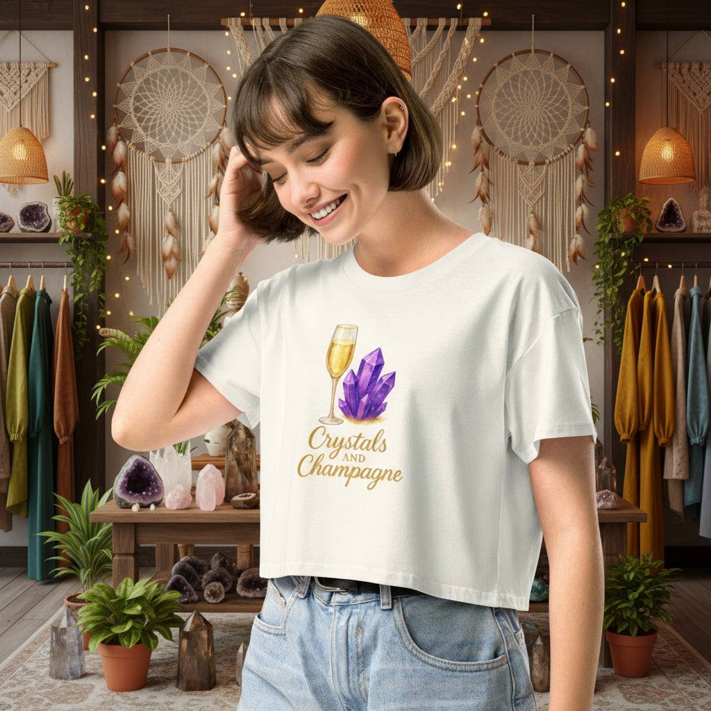 woman wearing Crystals and Champagne Women's Crop T-Shirt with champagne glass and purple crystals design in cozy boutique setting