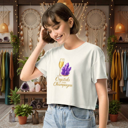 woman wearing Crystals and Champagne Women's Crop T-Shirt with champagne glass and purple crystals design in cozy boutique setting