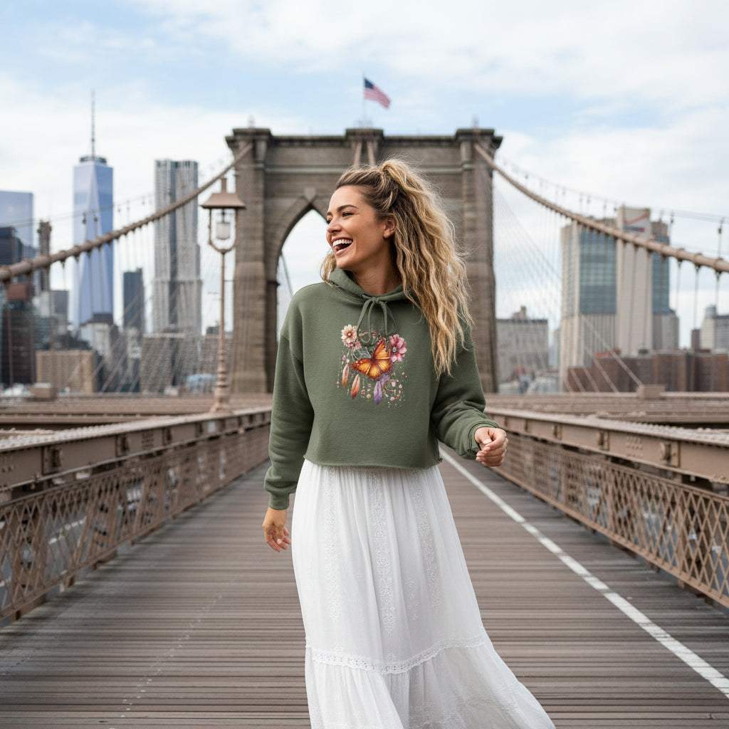 vrouwelijk model draagt groene cropped hoodie met boho vlinder en florale print op brug in stadscène