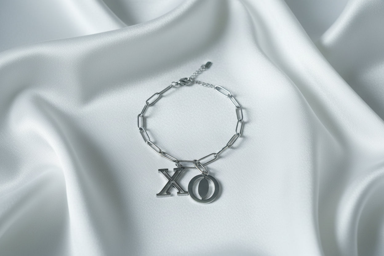 Zilverkleurige stainless steel schakelarmband van Glow Mystic in Style met grote X en O bedels op een wit satijnen kleed