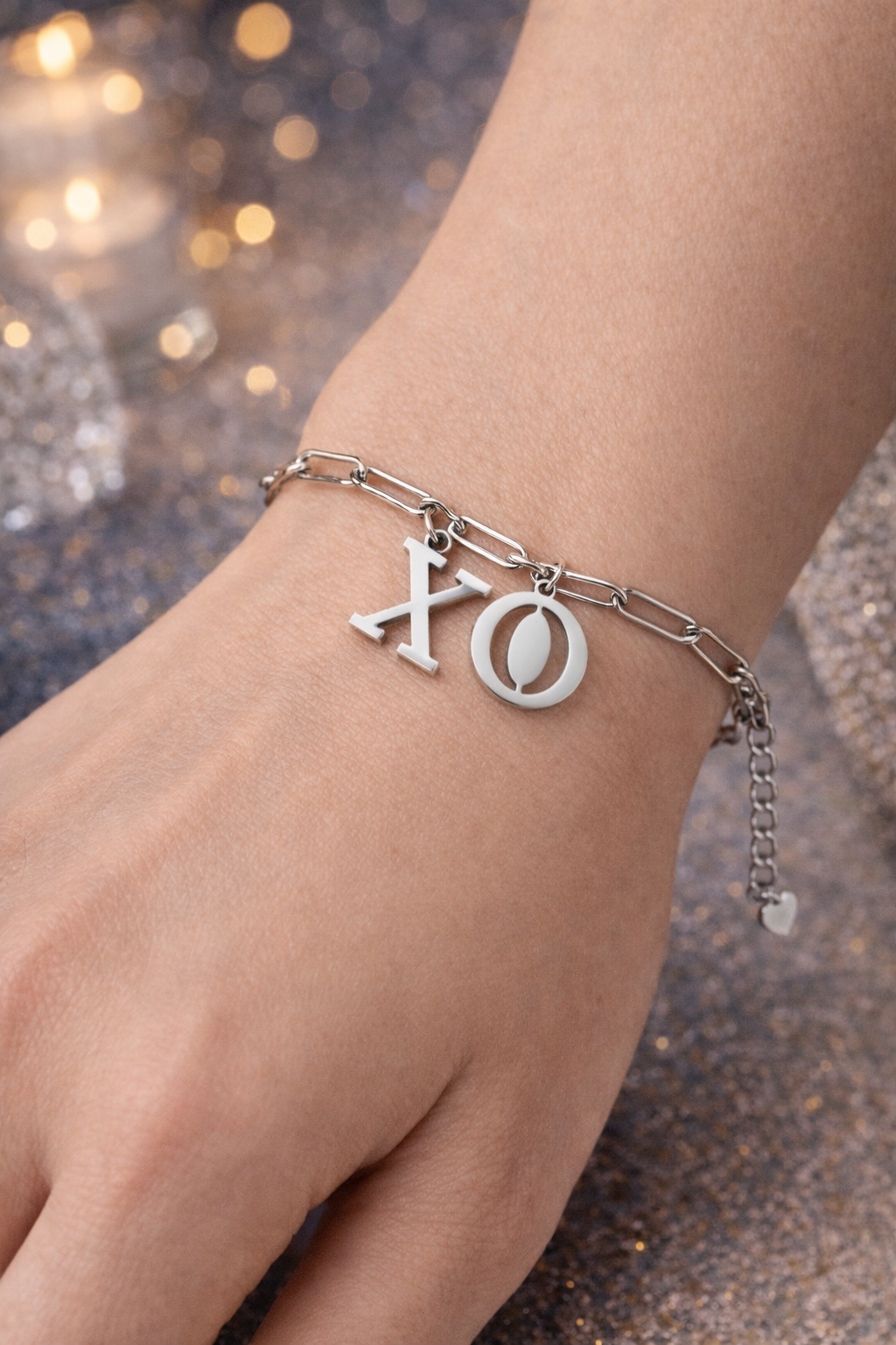 Zilverkleurige stainless steel schakelarmband van Glow Mystic in Style met grote X en O bedels gedragen om de pols van een jonge vrouw
