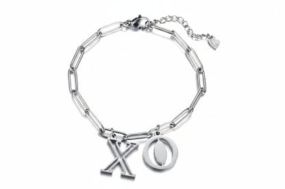 Zilverkleurige stainless steel schakelarmband van Glow Mystic in Style met grote X en O bedels tegen een witte achtergrond.