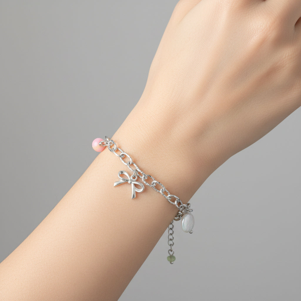 “Zilverkleurige statement armband met strikje, schelp en jade gedragen om de pols”