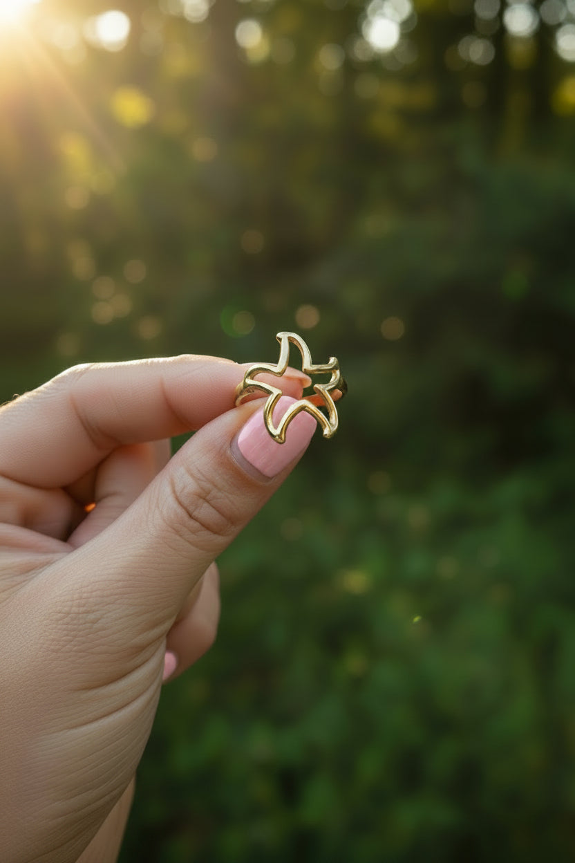 Sfeervolle close-up van de verstelbare gouden zeester ring vastgehouden in de hand tijdens een warme zonsondergang.
