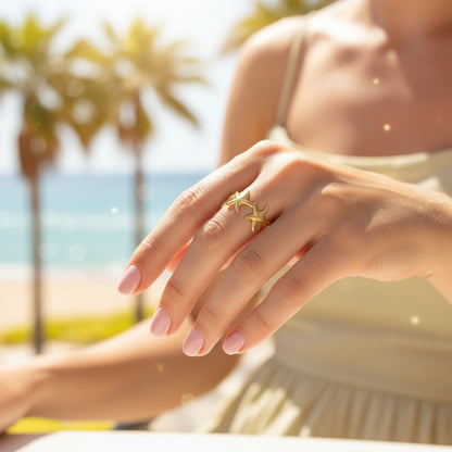 Elegante goudkleurige open zeester ring van waterproof RVS gedragen om de vinger van een vrouw op een zonnige dag op de boulevard.