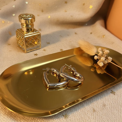 Close-up van Glow Mystic in Style zilveren hart oorbellen op gouden tray