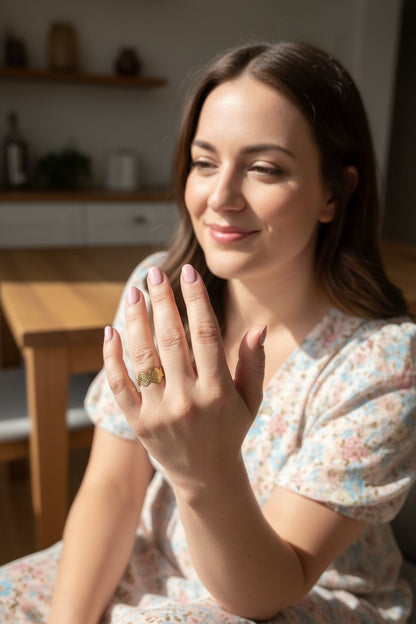 Vrouw met zachtroze nagellak toont een soleil ring met details.