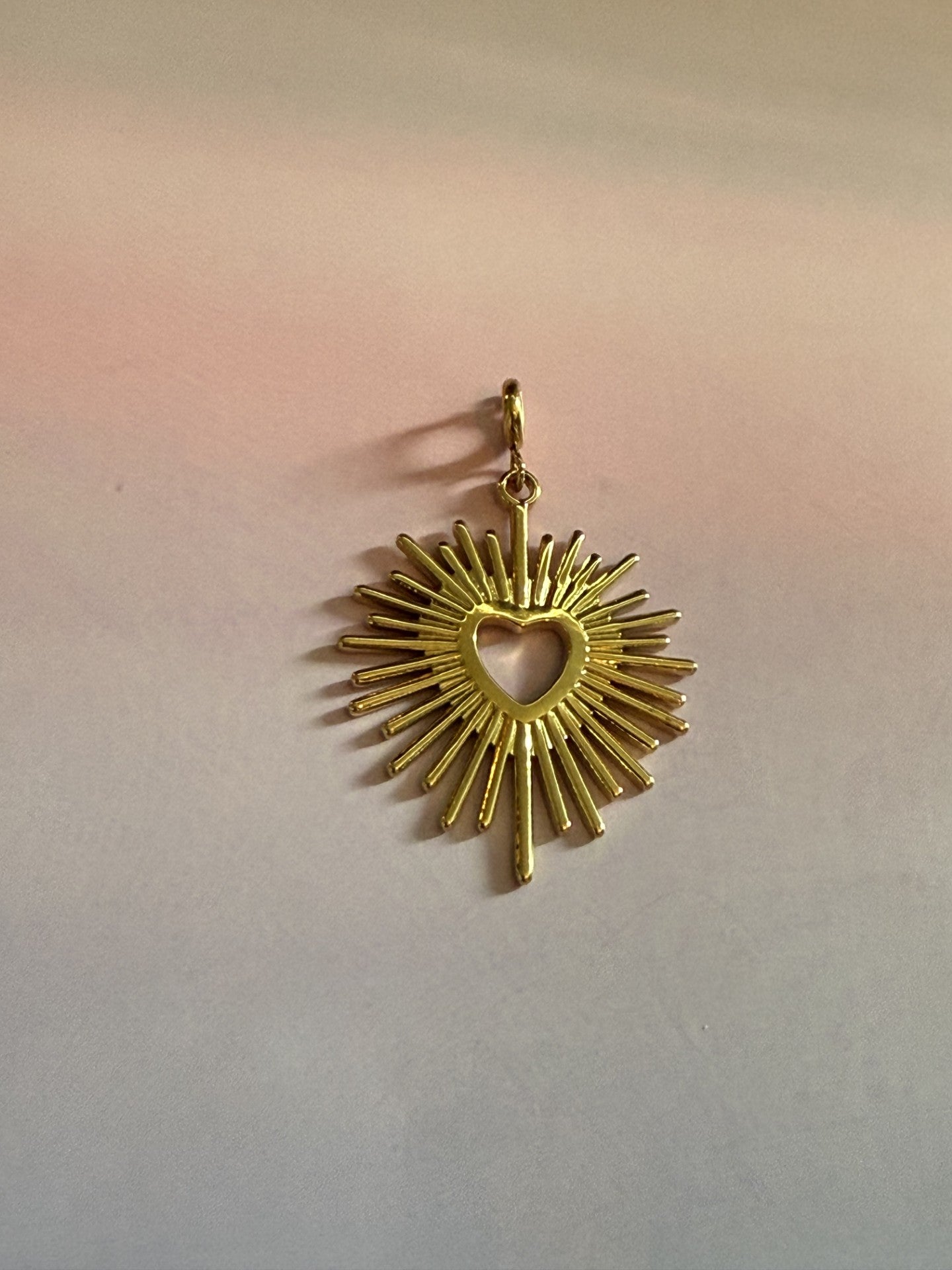 Luxe 14K vergulde zon hart bedel van roestvrij staal voor ketting op gekleurde chtergrond.