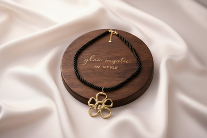 Elegante zwarte gedraaide koordketting met gouden bloemhanger.